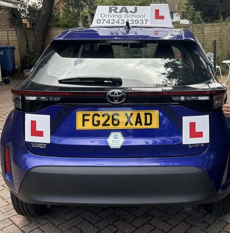 Rear of Raj's automatic Toyota Yaris lesson car with L plates and the Raj Driving School roof sign